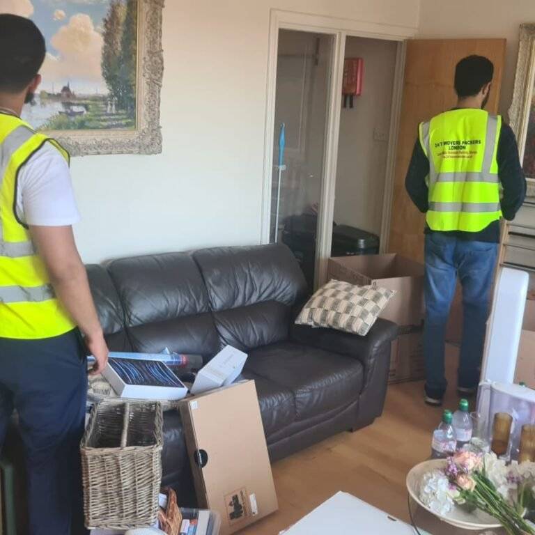 Two professional movers from 24/7 Movers Packers London packing household items and boxes during a home removal in North London.