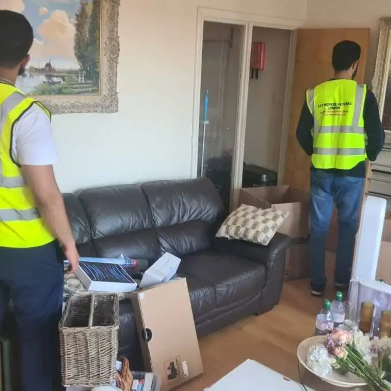 Two professional movers from 24/7 Movers Packers London packing household items and boxes during a home removal in North London.