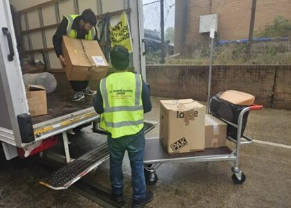 Two man are unloadingMaking Your Moves Memorable with our Top Notch Services the boxes from the truck in the trolley